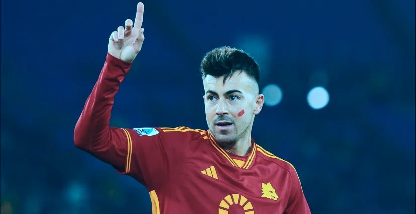 A male athlete wearing red uniform while raising his one hand up